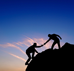 One person helping another up a mountain